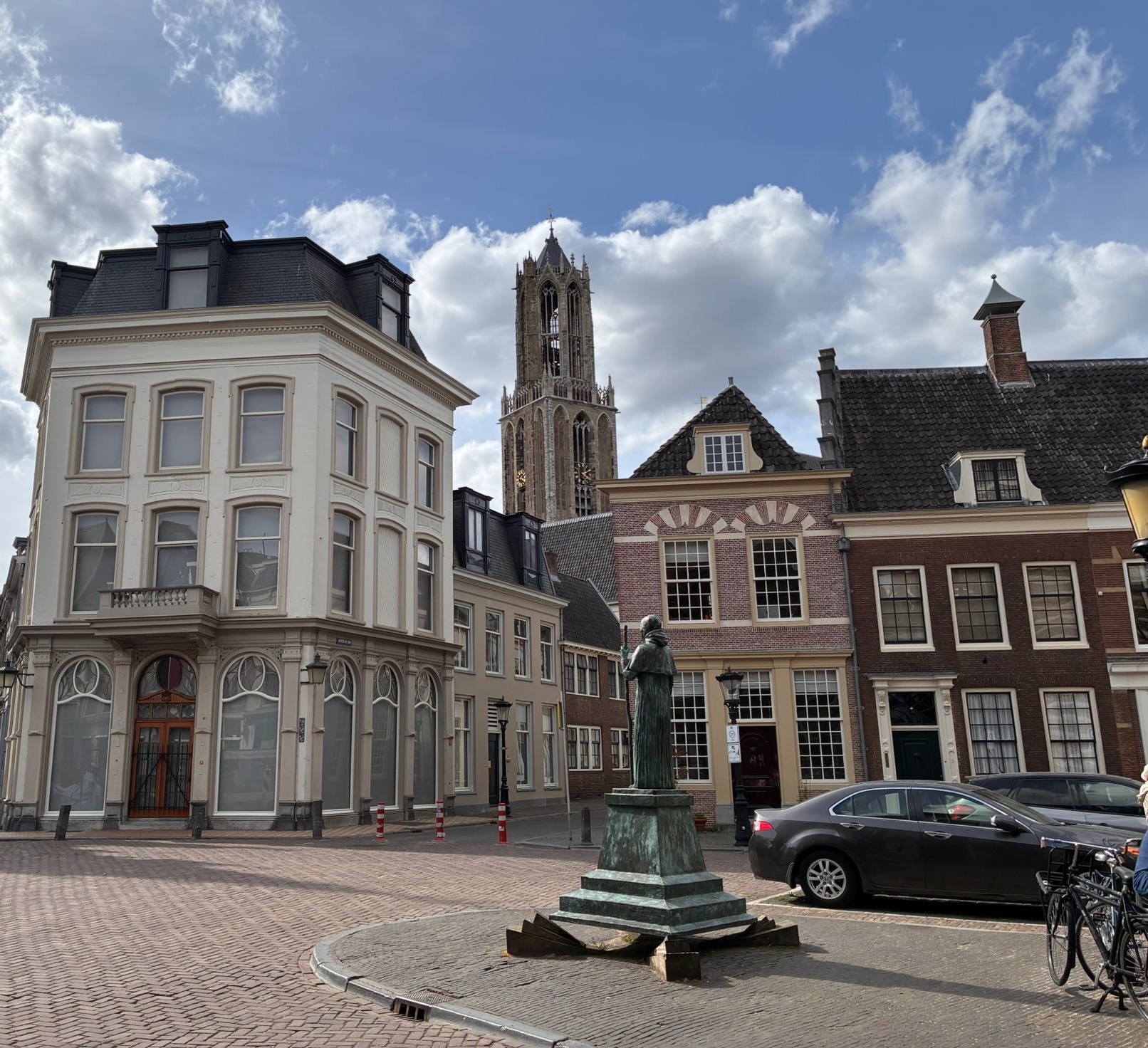 View of the Dom Tower from Pausdam square in Utrecht with historic houses and the statue of Pope Adrian VI